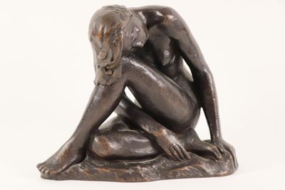 statue of a woman sitting on a rock with her hands on her knees