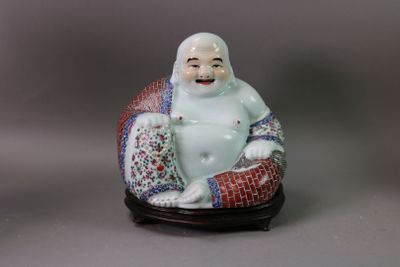 une figurine représentant un Bouddha souriant assis sur un coussin