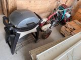 une photo d'un barbecue dans un garage, à côté d'un tas de bois