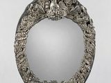 an ornate silver mirror on a stand with a flower design