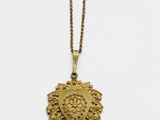 un collier en or avec un médaillon en forme de cœur suspendu à une chaîne