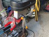 a drill on a table in a garage with other tools