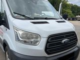 la camionnette blanche est garée sur un parking avec des arbres en arrière-plan