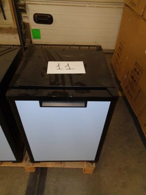 a black and white refrigerator sitting on a pallet in a warehouse