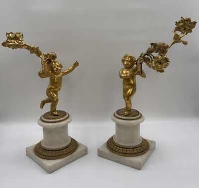 Paire de bougeoirs figurant deux angelots en bronze doré ten…