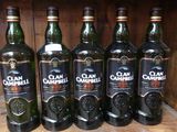 Six bouteilles de Clan Campbell sont alignées sur une étagère en bois.