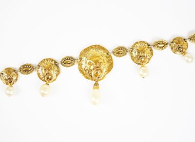 un gros plan d'un collier en or orné de perles sur fond blanc