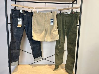 trois pantalons pour homme suspendus à un portant dans un magasin de vêtements