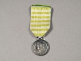 a silver medal with a green and white ribbon around it