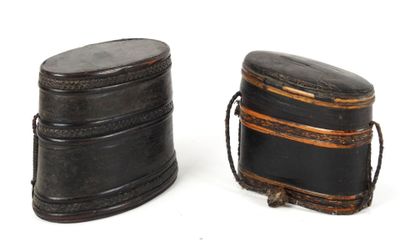 deux boîtes en cuir noir posées l'une à côté de l'autre sur une surface blanche