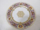 une assiette blanche ornée d'un motif doré et rose