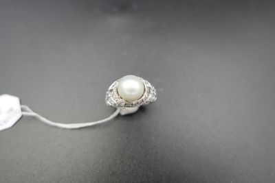 a close up of a ring with a pearl on a black surface