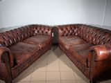 pair of leather chesterfield sofas in a room with tile flooring