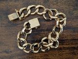a close up of a gold chain bracelet with a padlock on it