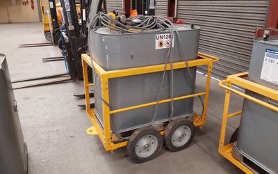 un petit chariot sur lequel est posée une machine, dans un entrepôt