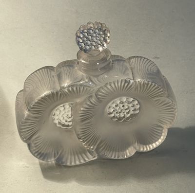 a clear glass perfume bottle with a flower on it