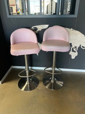 deux tabourets de bar roses devant une carte du monde