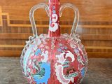 a red vase sitting on top of a wooden table
