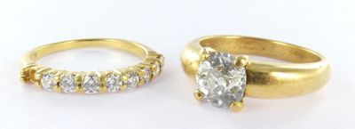 two gold rings with diamonds and a ring on a white surface