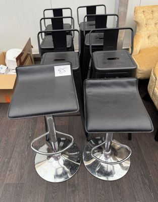 four black leather stools and a chair in a room