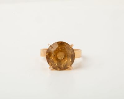 a close up of a ring with a brown stone on a white surface