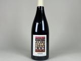 une bouteille de vin rouge posée sur une table blanche