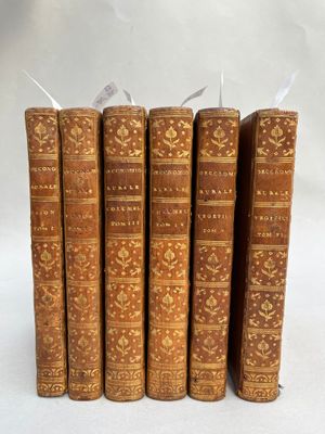 cinq vieux livres sont alignés sur une surface blanche