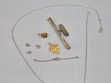 un collier en argent avec une chaîne en or et d'autres objets posés sur la table