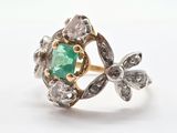 gros plan d'une bague avec une pierre verte entourée de diamants