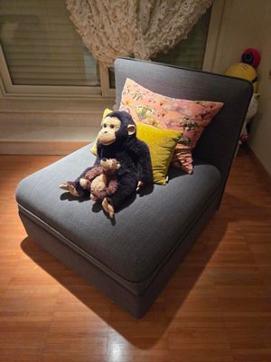 un singe en peluche assis sur une chaise dans un coin de la pièce
