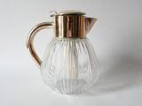 an image of a clear glass pitcher with a gold handle