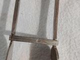 une pince métallique munie d'un manche, posée sur une surface blanche