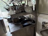 many pots and pans on the counter in this kitchen