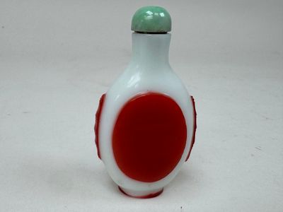 un petit vase rouge et blanc avec un couvercle vert