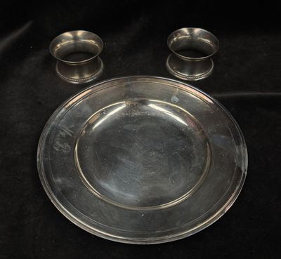 a silver plate and two silver cups on a black cloth