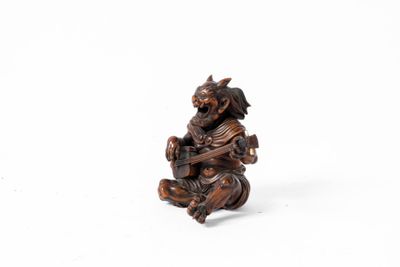une petite figurine en bois représentant un singe tenant une guitare
