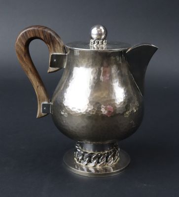 une cafetière en argent avec une poignée en bois sur fond noir