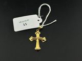 un pendentif en forme de croix en or avec une étiquette, sur fond noir