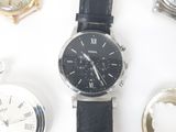 une montre noire posée sur une table, à côté d'autres montres