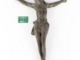 a bronze statue of a person on a cross with a green tag