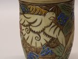 a vase with a bird on it sitting on a table