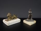 deux statues représentant un homme et un lion, posées sur un socle en marbre