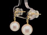 pair of earrings with pearls hanging from them on a black background
