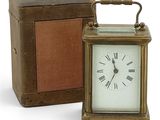 a small clock sitting next to a box on a white surface