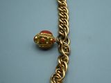 a close up of a gold bracelet with a bell on it