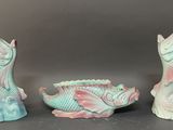 three figurines of fish and a fish bowl on a table
