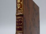 an old book sitting on top of a wooden table next to a white wall