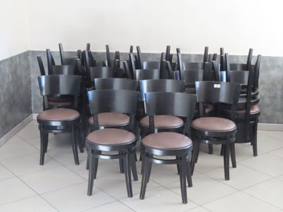 des rangées de chaises noires dans une pièce au sol carrelé de blanc