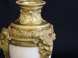 a gold and white vase sitting on top of a black table