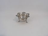 a small silver bowl with a handle on a white surface